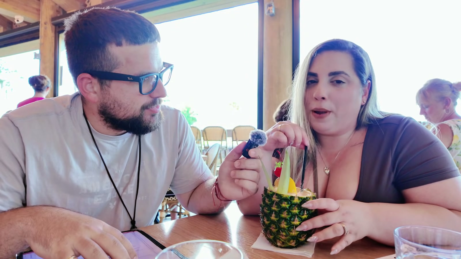 Gerardo y Diana en el comedor de Harry & The Natives, con The Buzzy Pineapple servido dentro de una piña sobre la mesa.